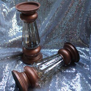 Two, copper colored, glass and metal candle holders stands.